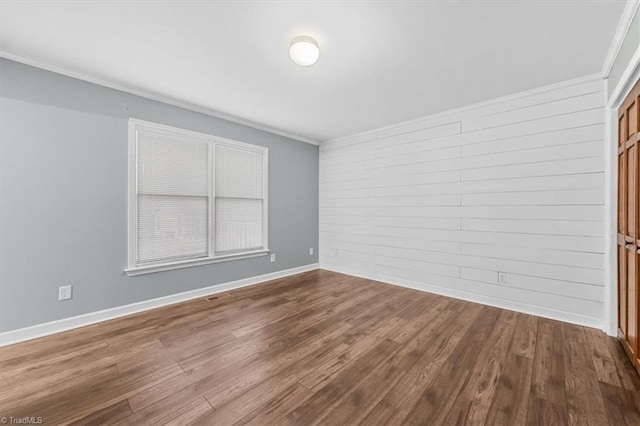 unfurnished room with dark wood-style floors, baseboards, and crown molding