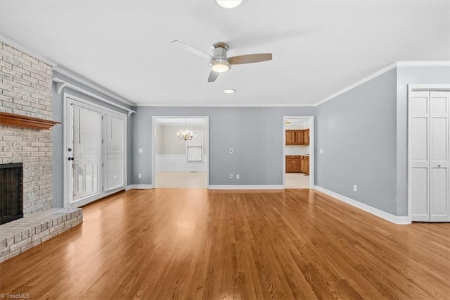 unfurnished living room featuring a fireplace, ornamental molding, wood finished floors, baseboards, and ceiling fan with notable chandelier