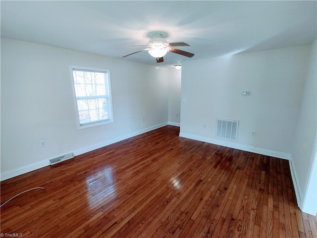 empty room featuring baseboards, visible vents, and dark wood finished floors