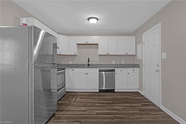 kitchen with light stone countertops, appliances with stainless steel finishes, dark wood-type flooring, sink, and white cabinetry