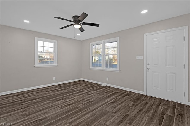 empty room featuring ceiling fan, a healthy amount of sunlight, and dark wood-type flooring