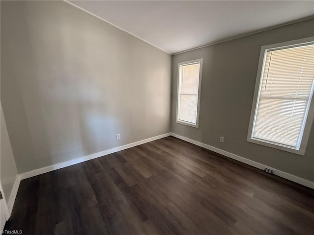 empty room featuring baseboards and dark wood-style flooring