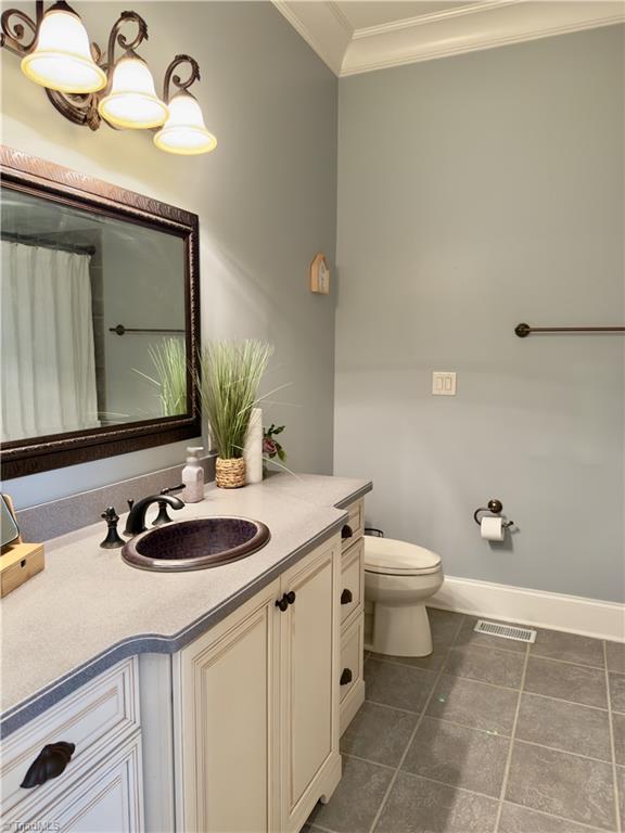 2863 Spencer Rd, Archdale, NC 27263 - full bathroom featuring ornamental molding, toilet, vanity, tile patterned floors, and baseboards