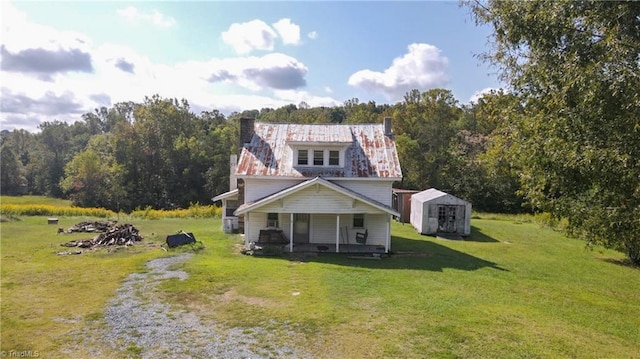 view of front of home featuring a front lawn, an outbuilding, a storage unit, and covered porch