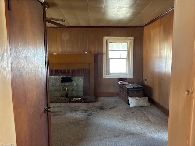 carpeted living area featuring wooden walls, a fireplace, and a ceiling fan