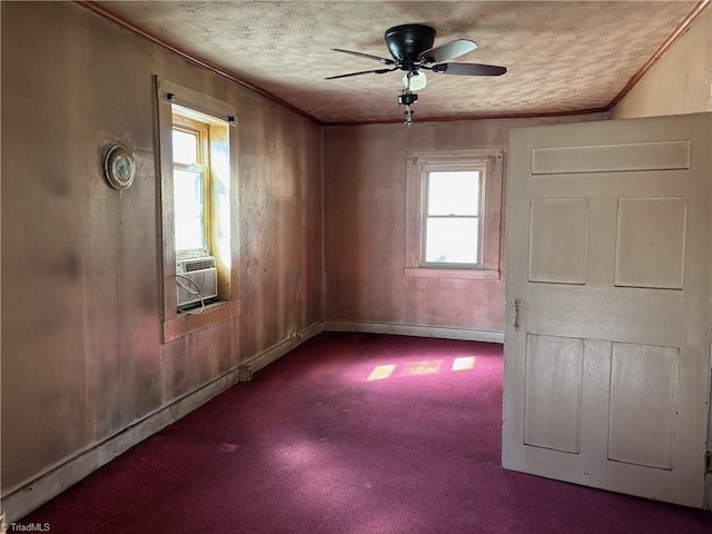 carpeted spare room featuring a textured ceiling, cooling unit, crown molding, baseboards, and ceiling fan