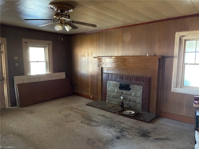 unfurnished living room with a wealth of natural light, wood walls, a fireplace, and carpet floors