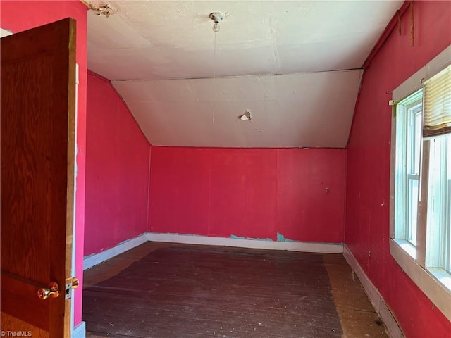 additional living space featuring baseboards, a healthy amount of sunlight, wood-type flooring, and vaulted ceiling