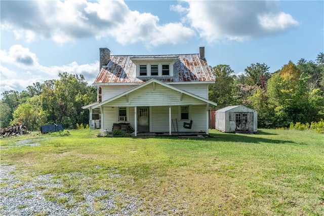 view of front facade with a front lawn, a porch, a chimney, and a shed