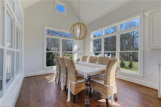 dining area featuring dark wood-style floors, high vaulted ceiling, a chandelier, and baseboards