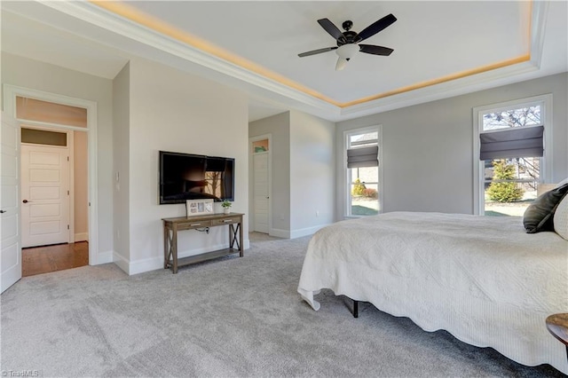 carpeted bedroom with multiple windows, baseboards, a raised ceiling, and a ceiling fan