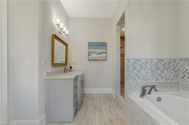 full bathroom with baseboards, wood finished floors, a bath, and vanity