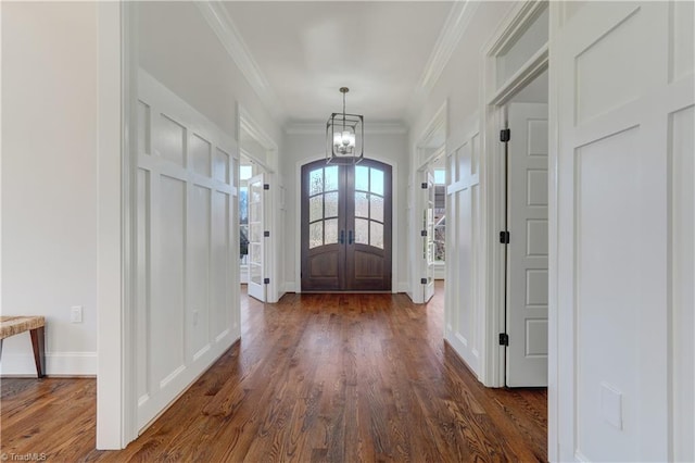 entryway with french doors, dark wood finished floors, an inviting chandelier, ornamental molding, and baseboards