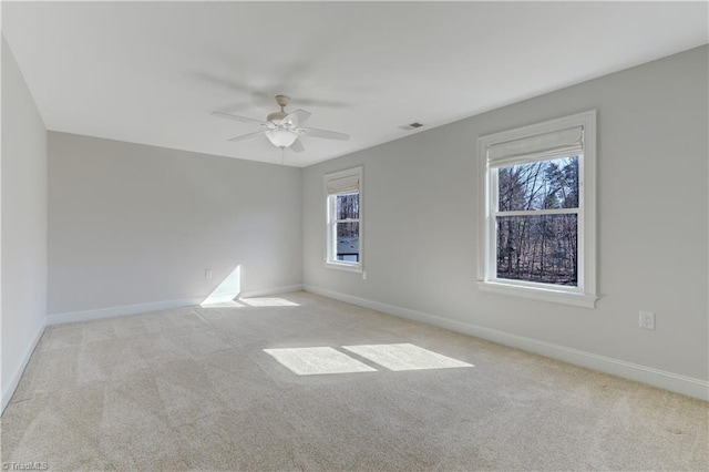 carpeted spare room with a ceiling fan, visible vents, and baseboards