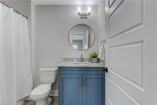 full bath with toilet, baseboards, wood finished floors, and vanity