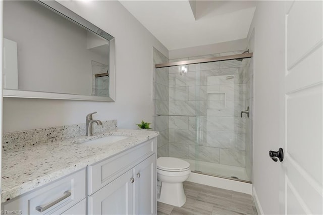 full bath featuring a stall shower, vanity, toilet, and wood finished floors