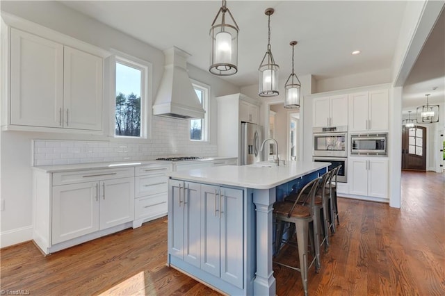 kitchen with white cabinetry, custom range hood, and appliances with stainless steel finishes