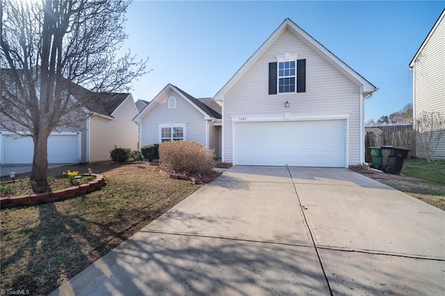 traditional home featuring a garage, concrete driveway, and fence