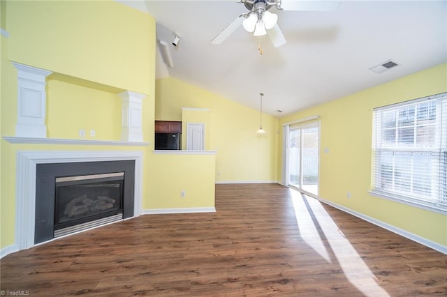 unfurnished living room with visible vents, baseboards, dark wood finished floors, vaulted ceiling, and a glass covered fireplace