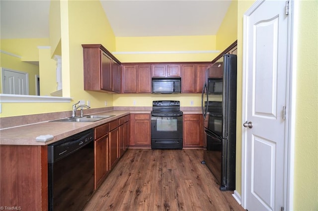 kitchen with dark wood finished floors, black appliances, light countertops, and a sink