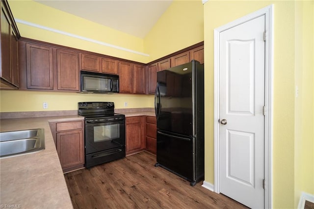 kitchen with light countertops, vaulted ceiling, dark wood-style floors, black appliances, and a sink