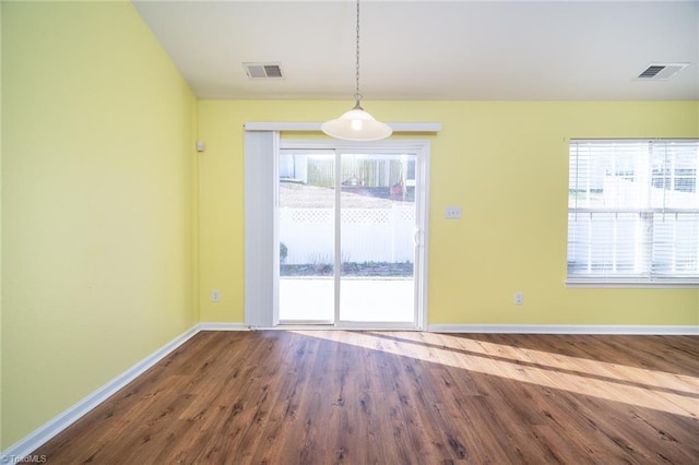 spare room with visible vents, baseboards, and wood finished floors