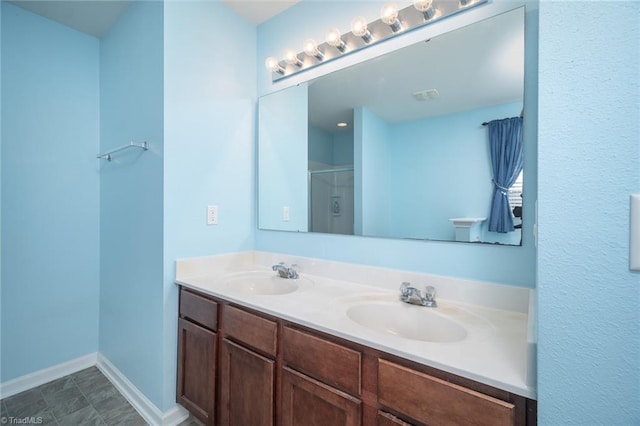 full bathroom with a sink, baseboards, double vanity, and a shower stall