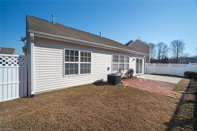 back of house with fence, central AC, roof with shingles, a yard, and a patio