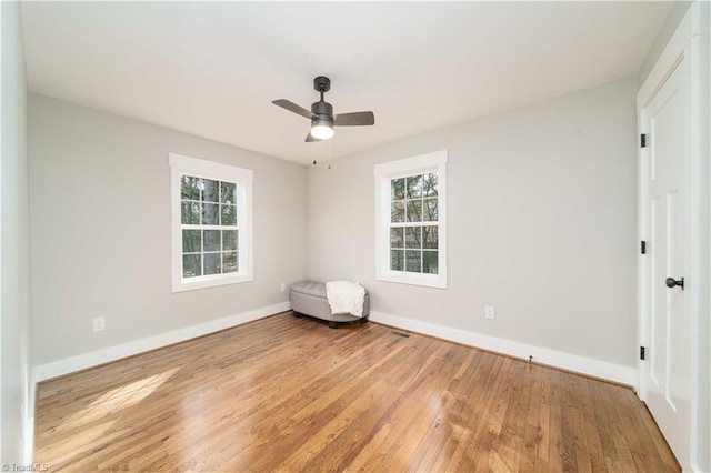 empty room with visible vents, baseboards, ceiling fan, and hardwood / wood-style flooring