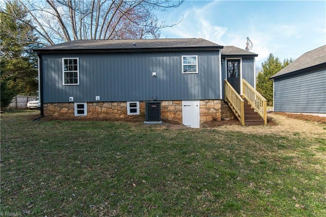 back of property featuring entry steps, a lawn, and a shingled roof