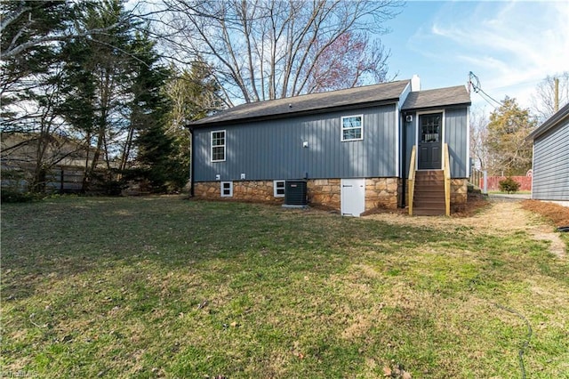 rear view of property featuring central AC unit, a lawn, entry steps, and fence