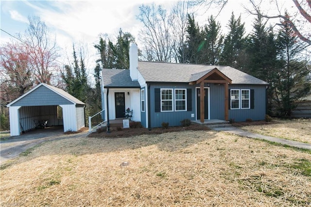 ranch-style home featuring a detached carport, a chimney, a shingled roof, a front lawn, and aphalt driveway