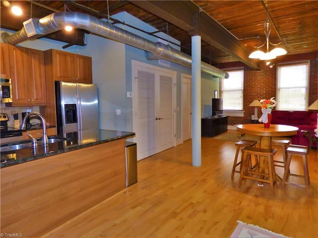 836 Oak St Unit 301, Winston-Salem, NC 27101 - kitchen with appliances with stainless steel finishes, brown cabinets, light wood-type flooring, brick wall, and wooden ceiling