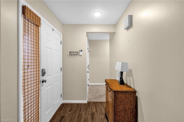 interior space featuring dark wood-style floors, a textured ceiling, and baseboards