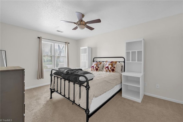 bedroom featuring light carpet, a textured ceiling, visible vents, and baseboards