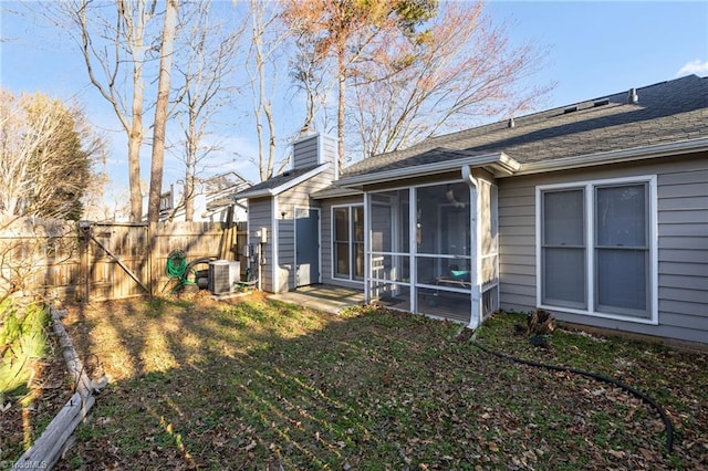 back of property with a yard, a chimney, a sunroom, fence, and cooling unit