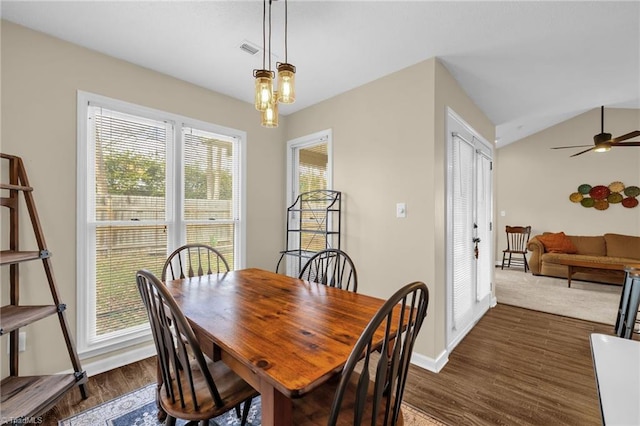 dining room with dark wood finished floors, visible vents, vaulted ceiling, baseboards, and ceiling fan with notable chandelier