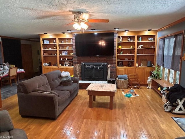 living room featuring crown molding, a fireplace, hardwood / wood-style floors, a textured ceiling, and a ceiling fan