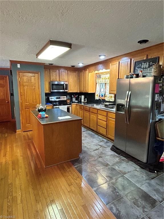 kitchen with brown cabinetry, stainless steel appliances, and a textured ceiling