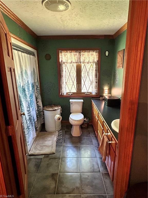 bathroom with vanity, curtained shower, toilet, a textured ceiling, and tile patterned floors