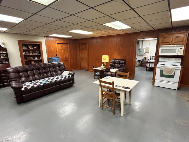 living area featuring wooden walls, built in features, concrete floors, and a paneled ceiling