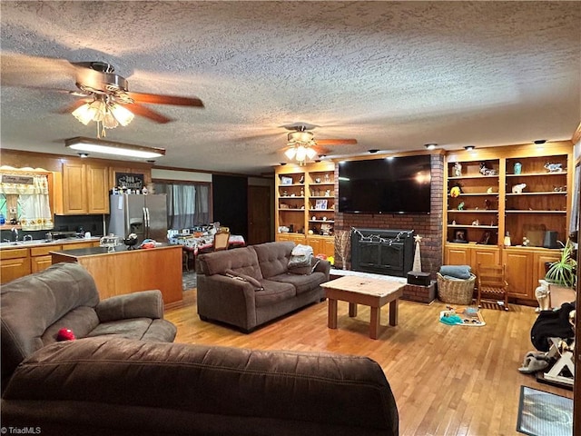 living area featuring light wood-style floors, a ceiling fan, a textured ceiling, and a fireplace