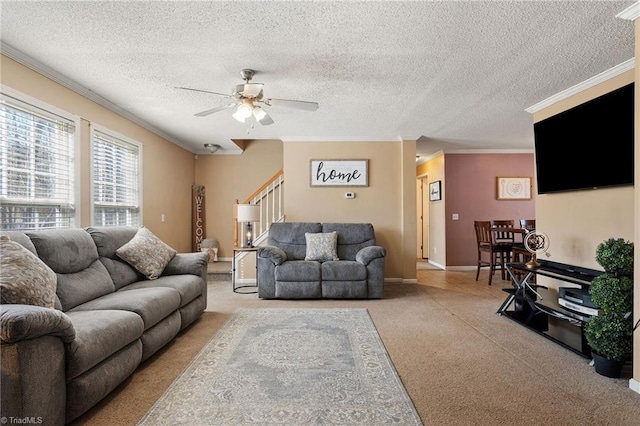 living room featuring stairway, baseboards, ceiling fan, ornamental molding, and a textured ceiling