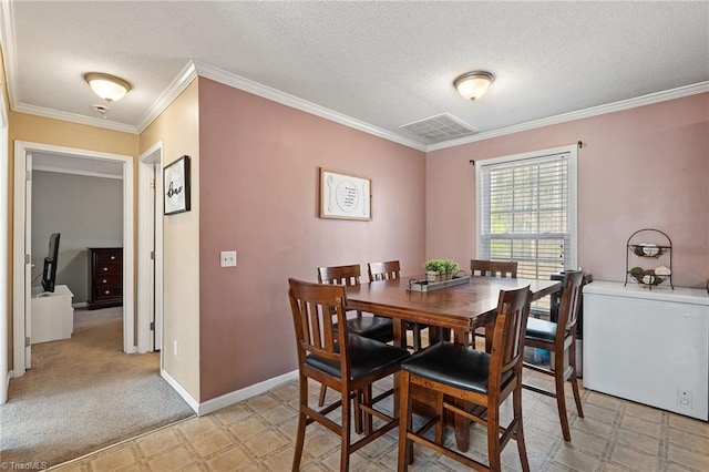 dining room with baseboards, visible vents, ornamental molding, a textured ceiling, and light carpet