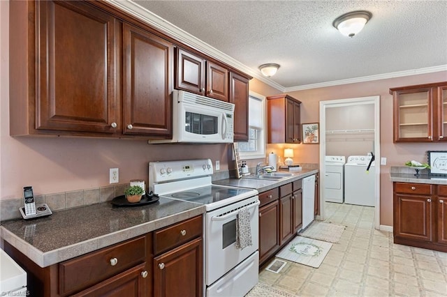 kitchen featuring washer and dryer, a sink, white appliances, glass insert cabinets, and light floors