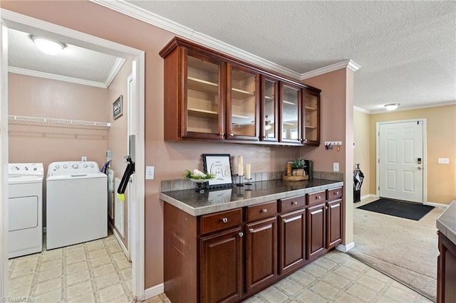 kitchen with ornamental molding, a textured ceiling, washing machine and dryer, glass insert cabinets, and light floors