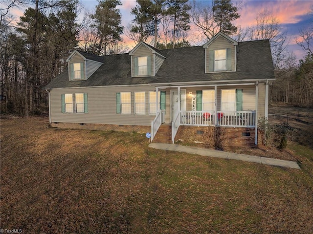 cape cod house featuring crawl space, roof with shingles, covered porch, and a front yard