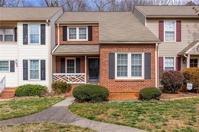 view of property with a front yard, covered porch, and brick siding