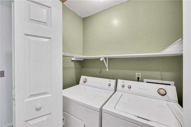 washroom with laundry area, a textured ceiling, and washer and dryer