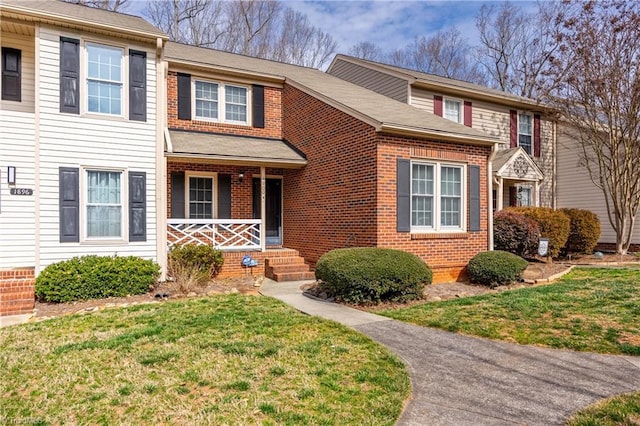 multi unit property with a porch, a front yard, and brick siding